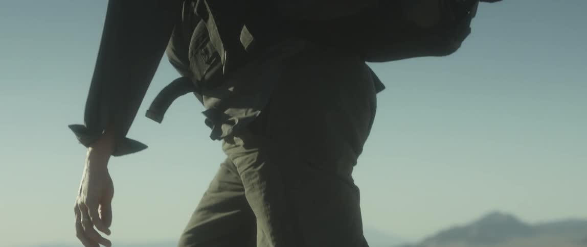 A man is walking up a sandy hill in the desert