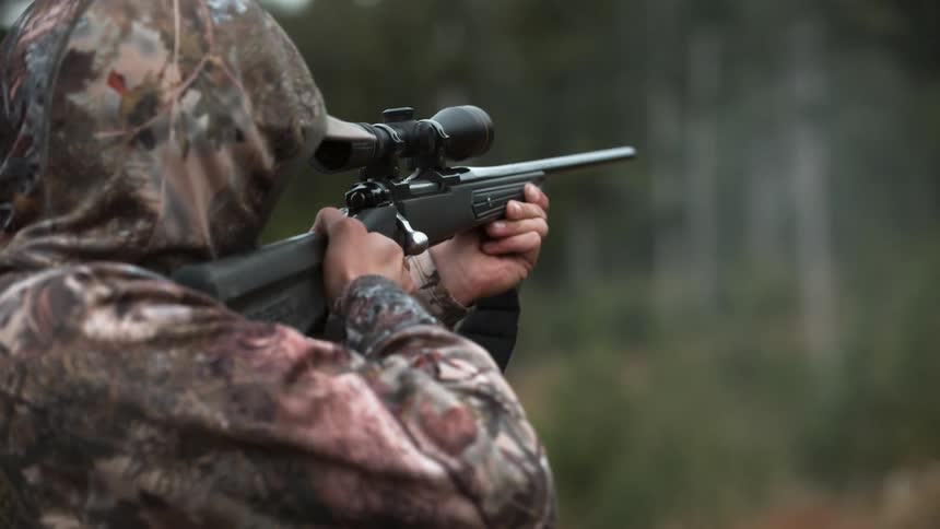 Person wearing camouflage shoots a gun