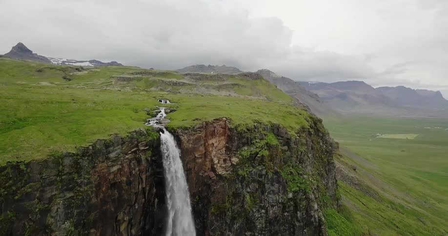 A stream gushes over a rocky cliffside on a cloudy day