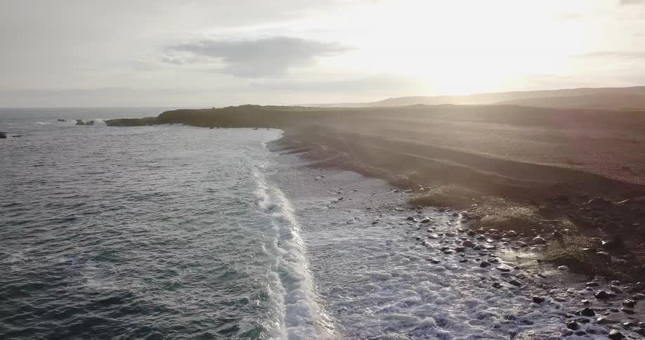 Ocean waves crash ashore at sunset