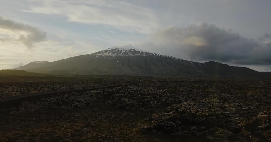 Clouds float near a snowy mountain peak