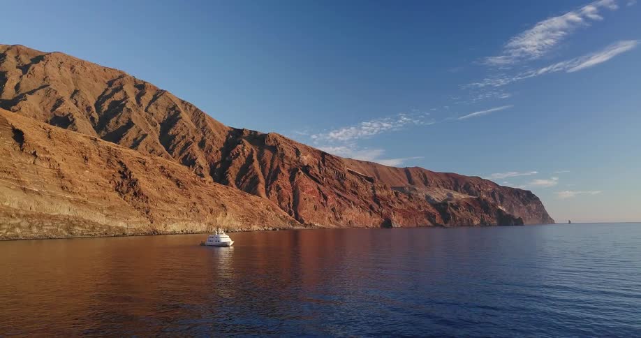 A yacht sits in a secluded bay during the day