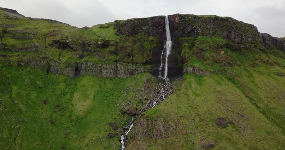 A waterfall from a large mountain flowing to a creek