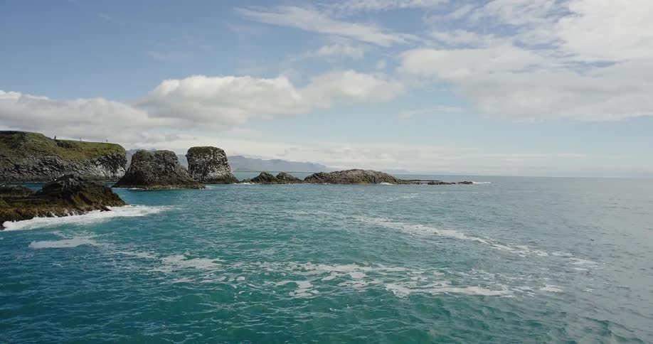 Ocean water ripples and flows around rock formations on the coast
