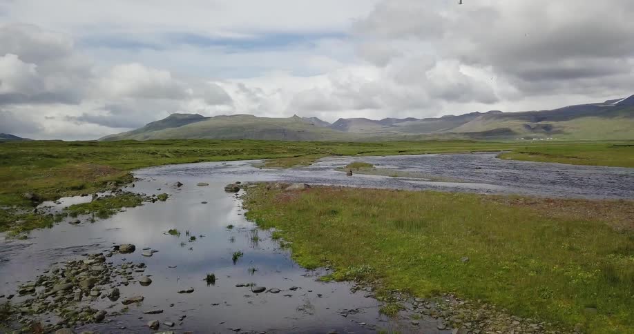 A small lake surrounded by rocky grass