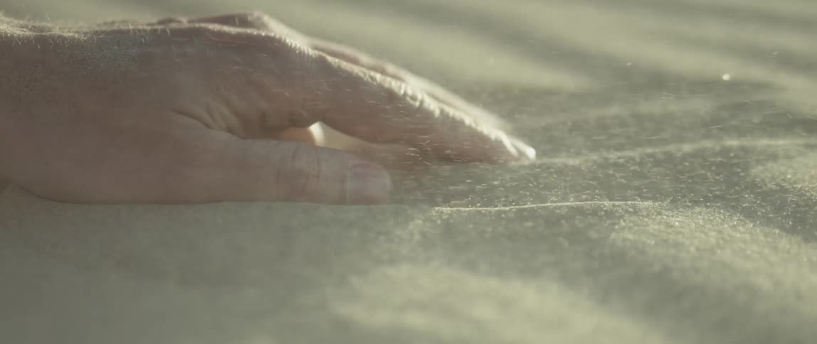 A hand on some sand as it blows all over