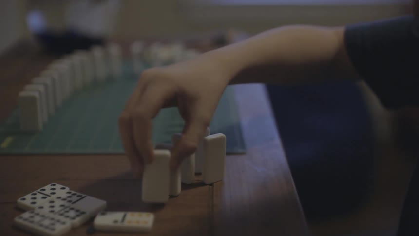 A person setting up dominoes