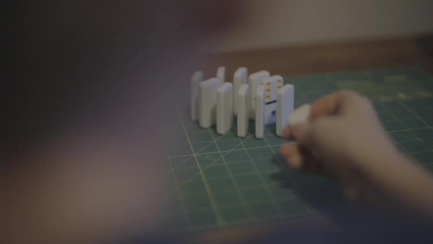 Person stacking dominoes in a row