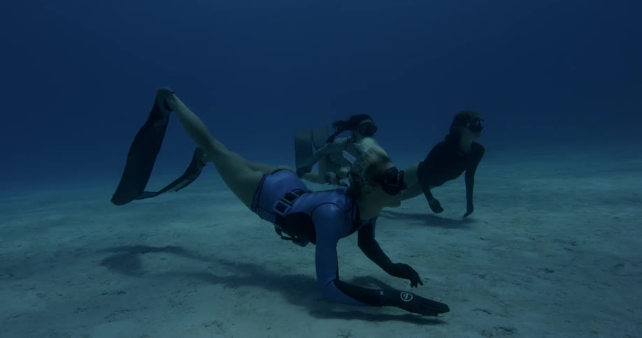 Female divers swim near the ocean floor