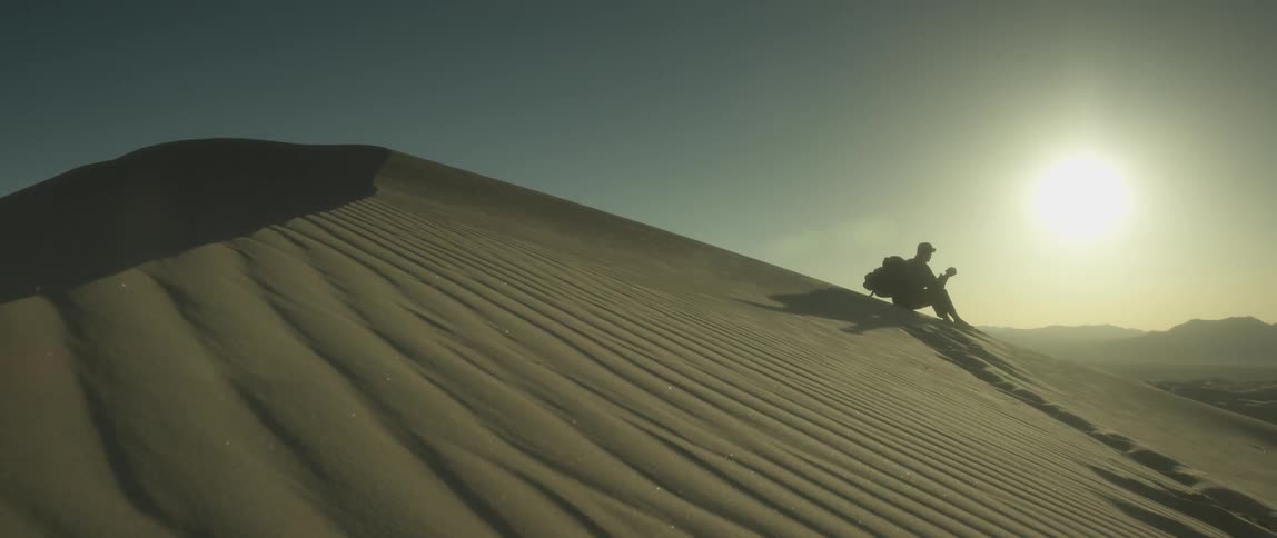 A person sitting on a sand dune