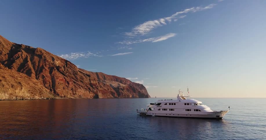 A yacht sits in a secluded bay during the day