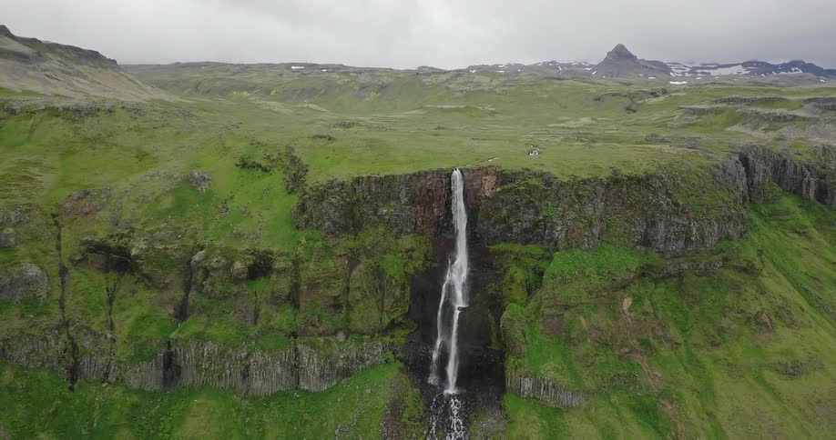 Slim waterfall on a high grassy area on a cloudy day