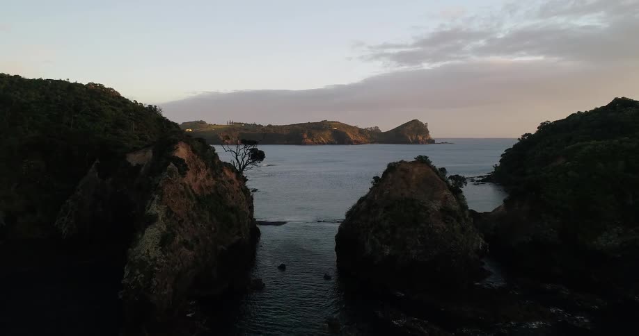 Water flows around land masses just off the coast at sunset