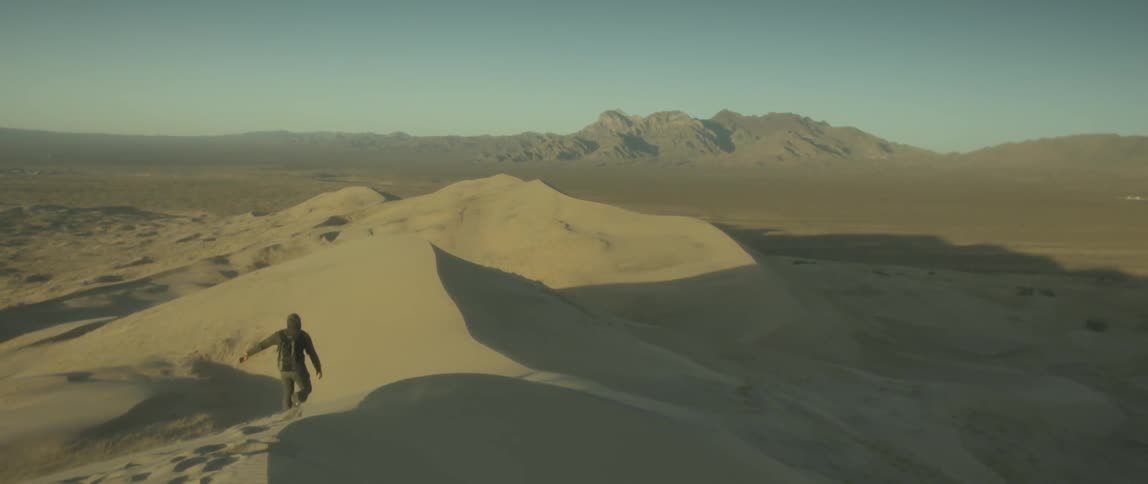 Man hiking through sand dunes in the desert