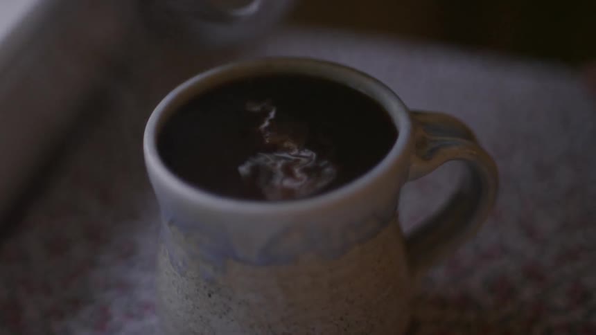 Cream being poured into a cup of coffee