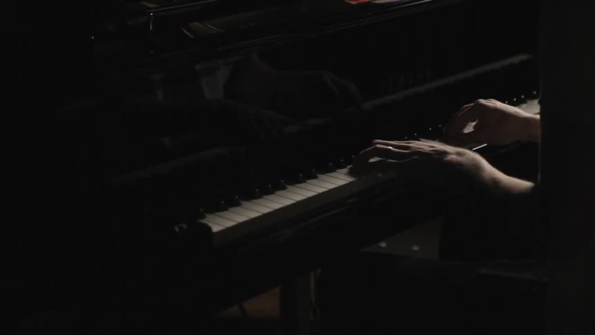 Person playing a piano in a dark area