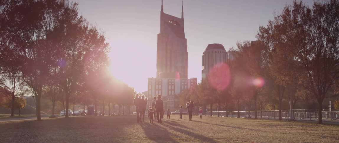 People walking towards a tall building at sunrise