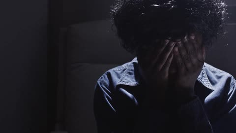 Woman sitting down slowly covers her face with her hands