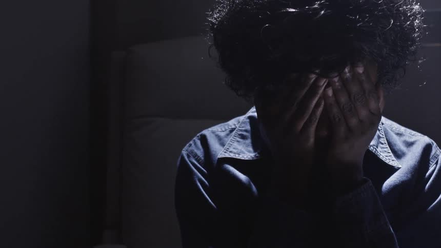 Woman sitting down slowly covers her face with her hands