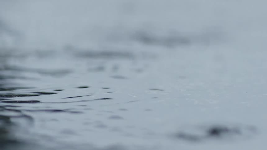 Raindrops falling into the water as it begins sprinkling