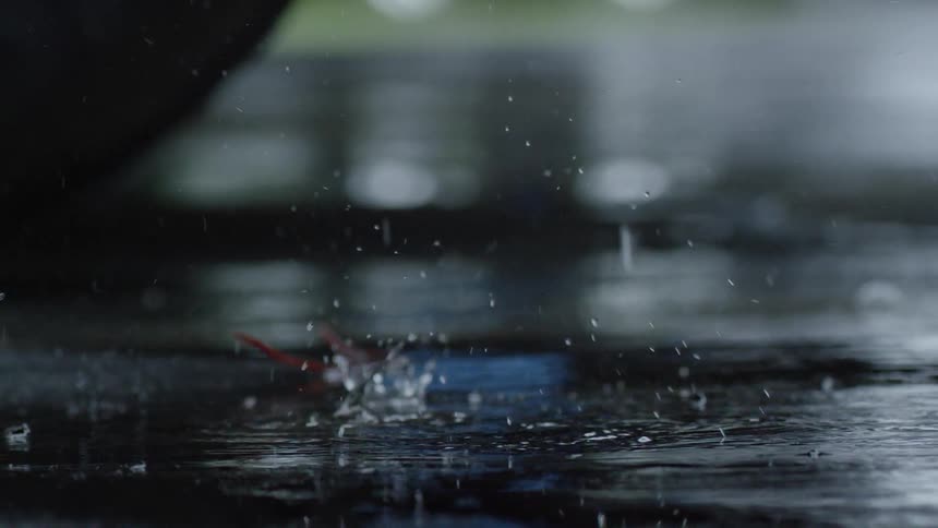 Close up shot of rain drops hitting pavement