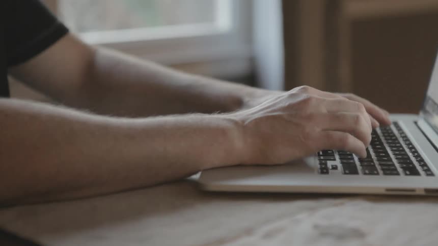 A man types on a laptop