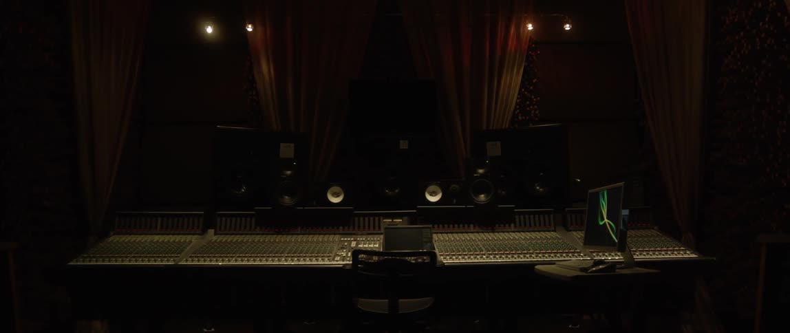 Speakers and a computer monitor sit by a sound mixing board