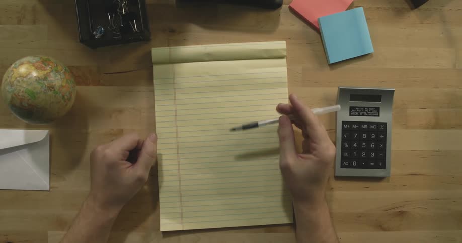 A person taps a pen on a legal pad