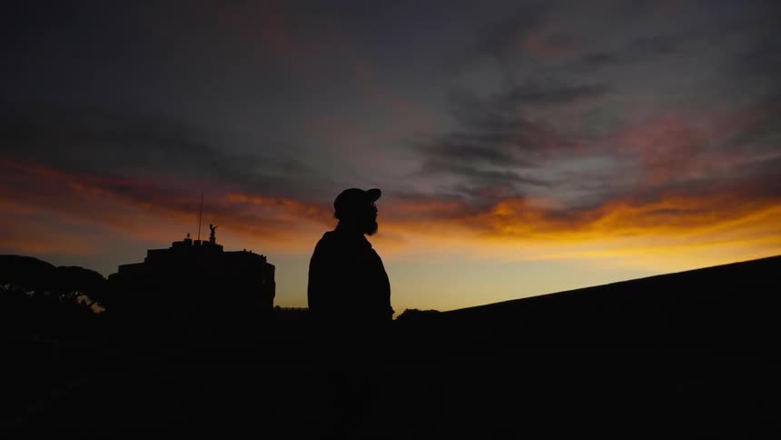 The silhouette of a man standing outside at sunset