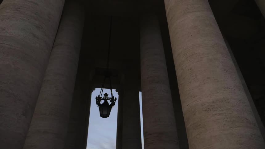 Large pillars of a building with an ornate object hanging in the middle