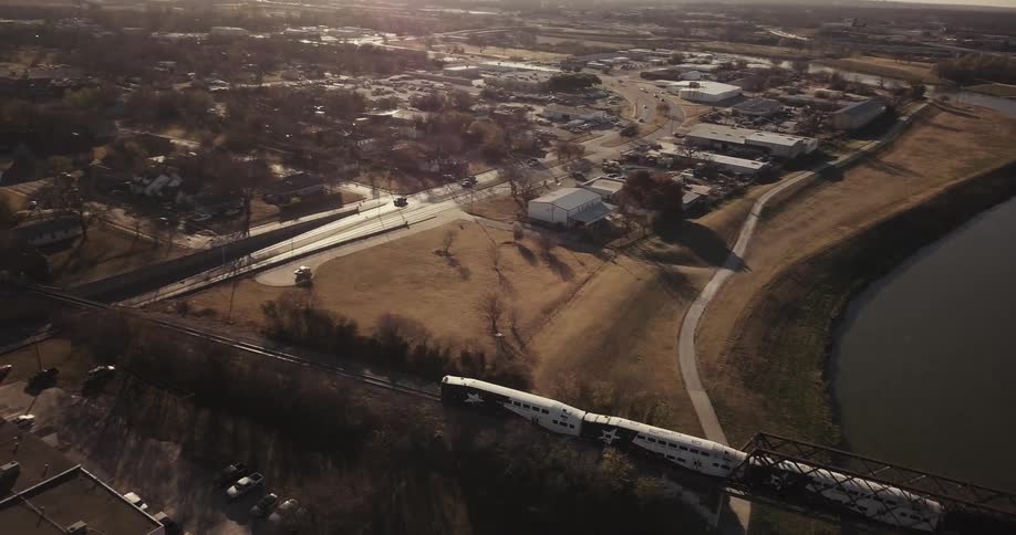 Train speeding over a river out of a city