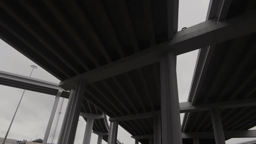 An overcast, gray sky hangs above a complex freeway system during the day