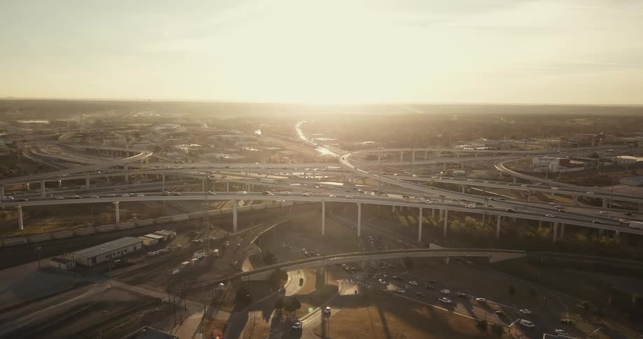 Cars drive on city roads at sunset