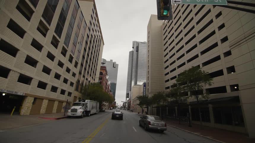 Cars are driving down a street in a city during the day