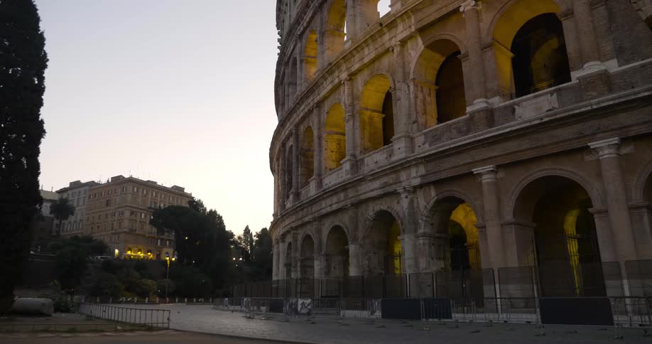 A truck passes by an old roman ruin at dusk