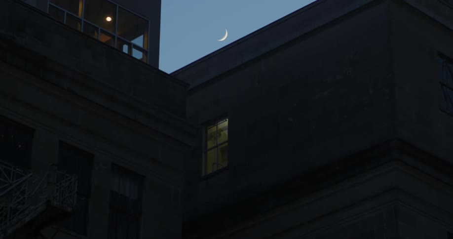 Moon above a dark building at night