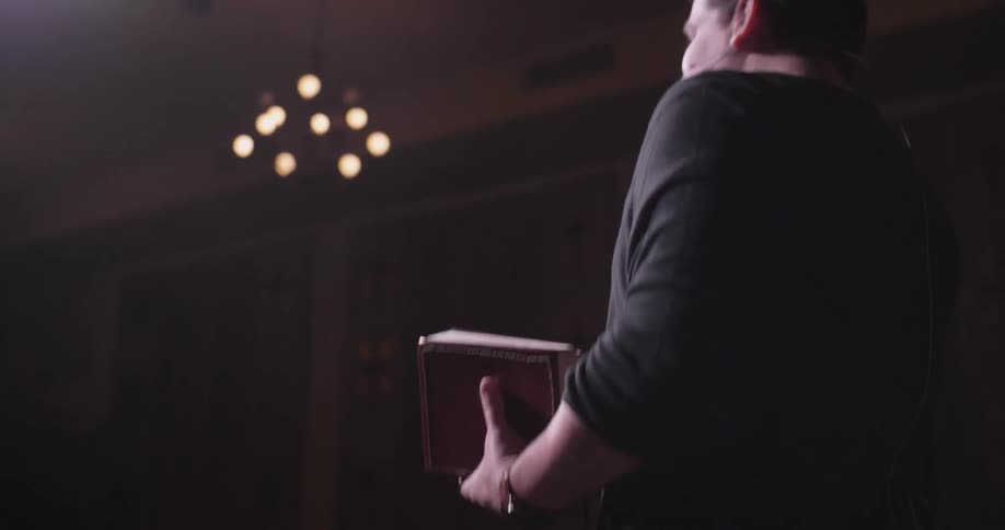 A man is giving a speech holding a book