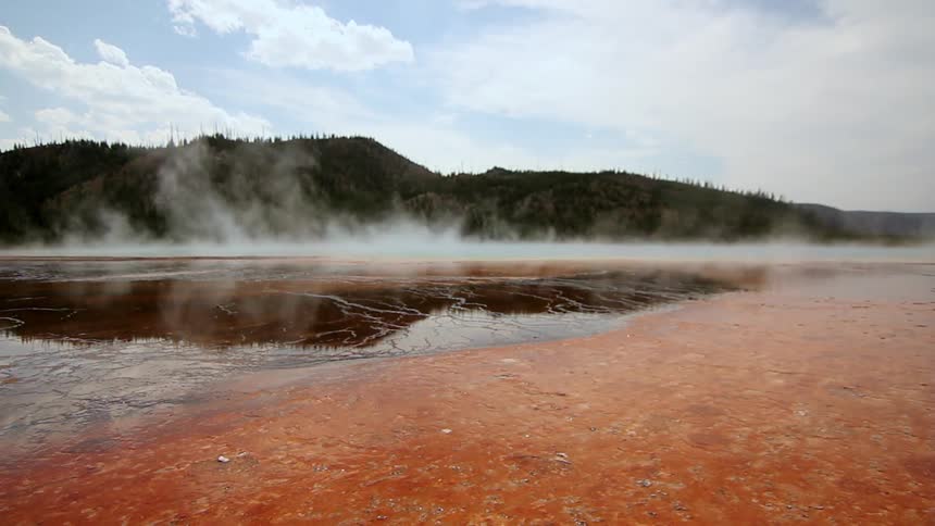 Steam is rising off the water by the shore