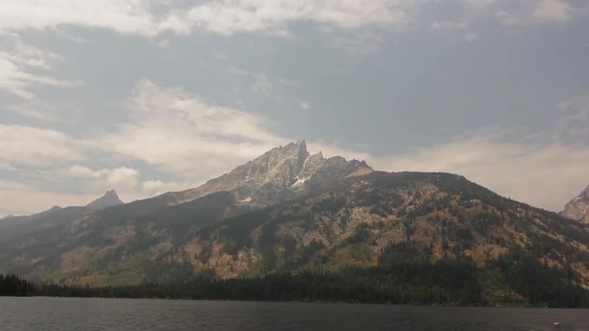 There is a tall green mountain past the water