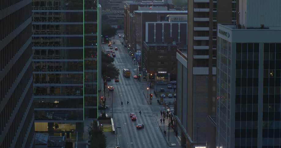 Cars drive on a city street at dusk