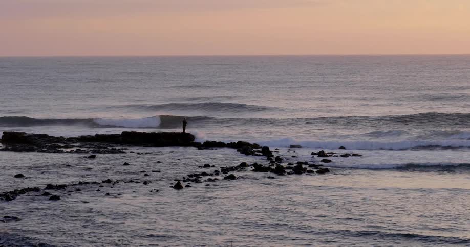 Person standing at a rocky edge of the ocean