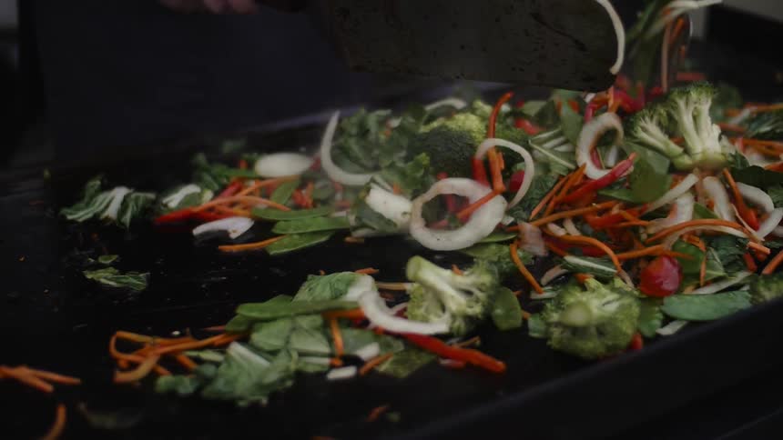 Vegetables are cooked on a hot grill