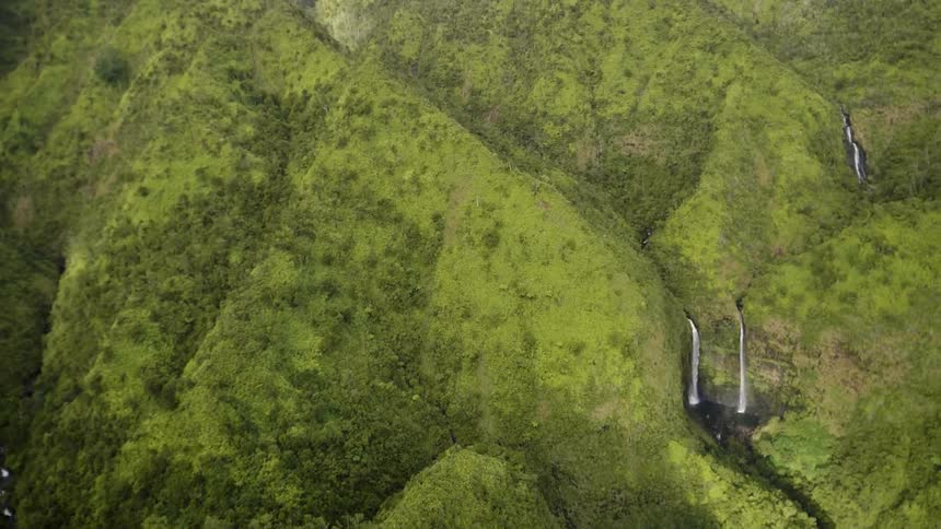 Waterfalls flow on green mountain peaks