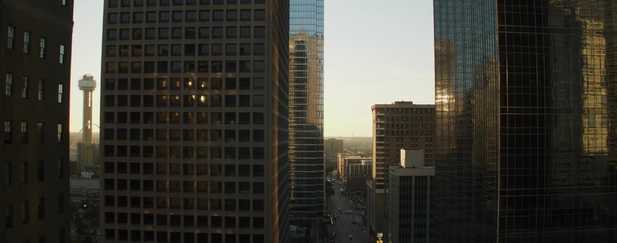 The buildings are tall and reflecting the setting sun