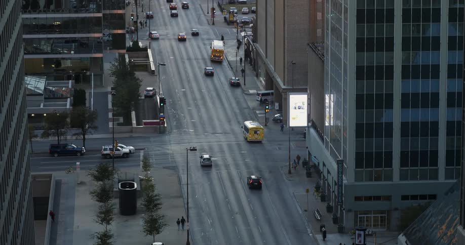 Traffic flows down a street in a city at dusk