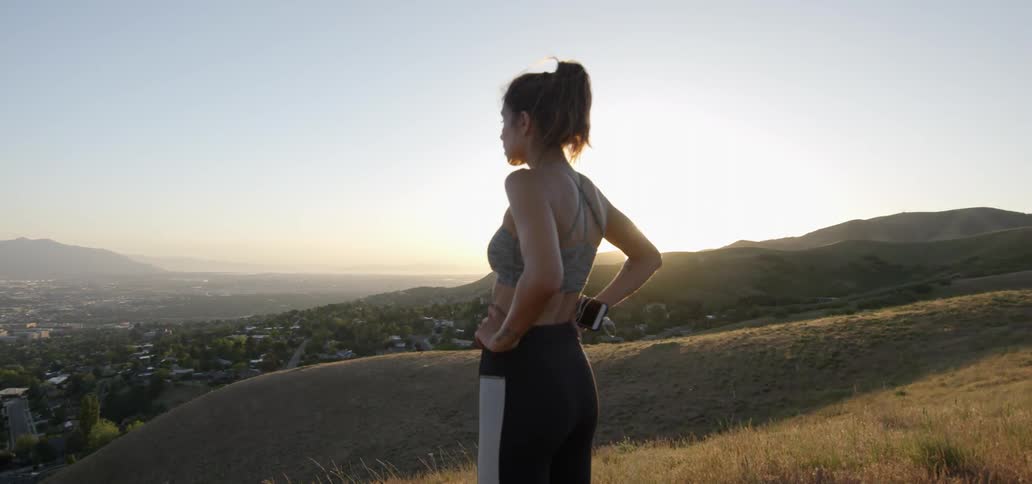 Woman standing on a hilltop looking down at a city
