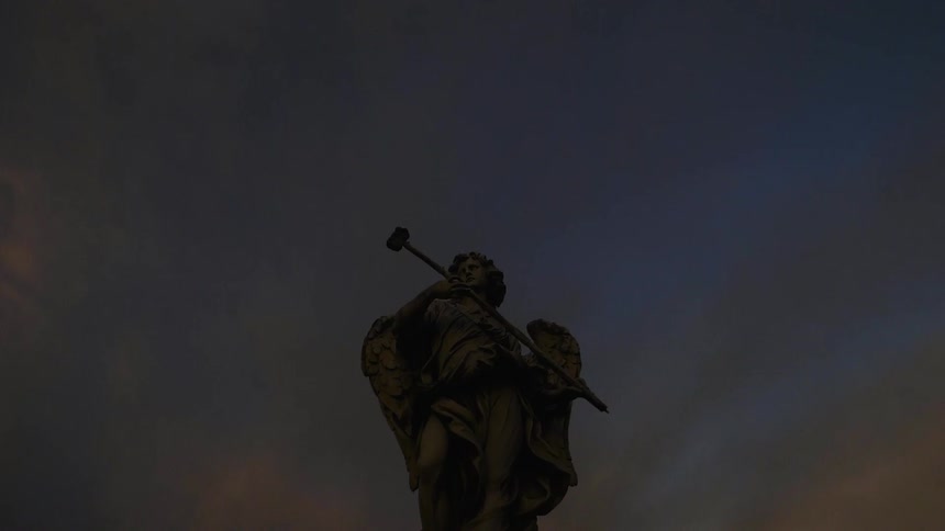 An angel statue stands overhead at sunset