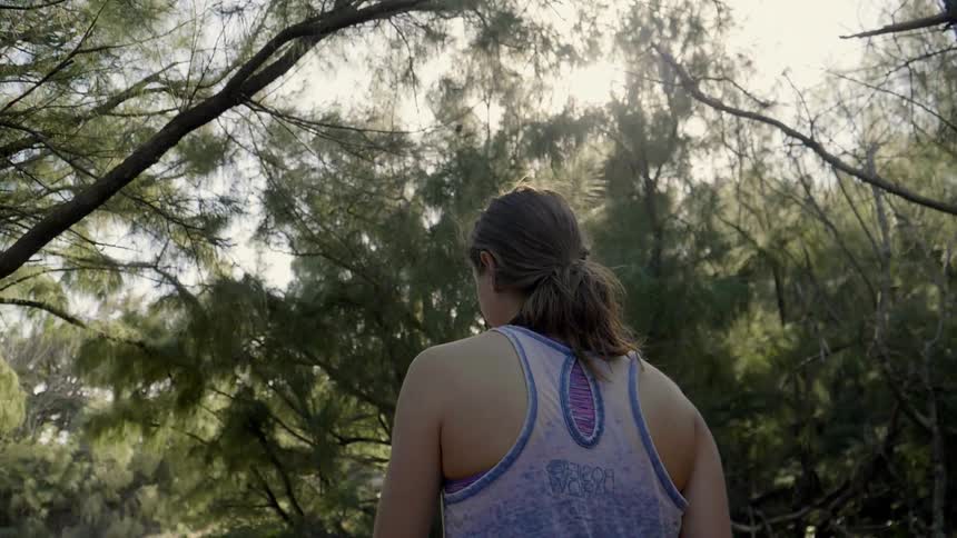 A woman walks through through some trees during the day