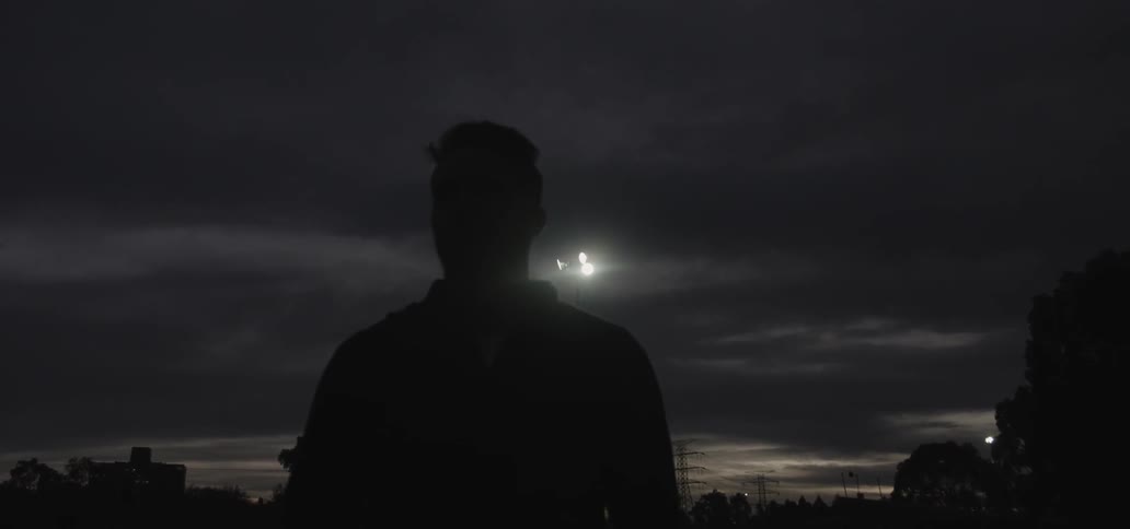 Silhouette of a man walking outside at night