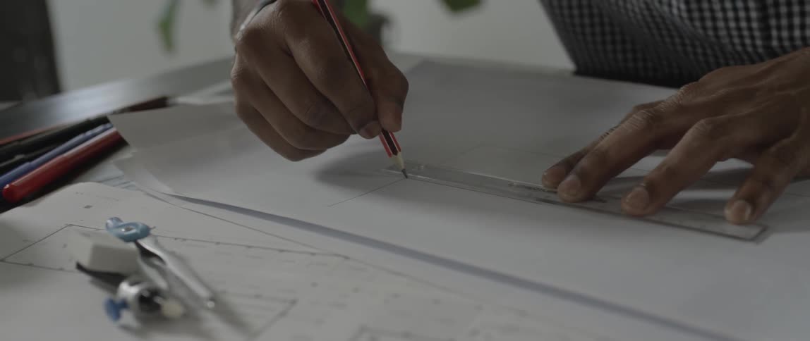 Person draws a line against a ruler with a pencil